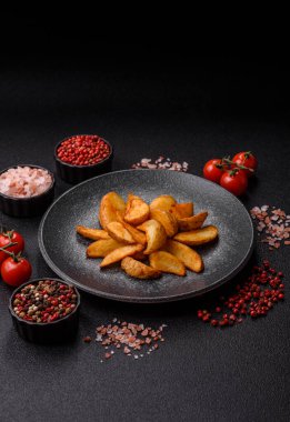 Biberiye, peynir, tuz ve baharatlı ızgara patates dilimleri. Koyu beton zeminde fırında patates dilimleri.