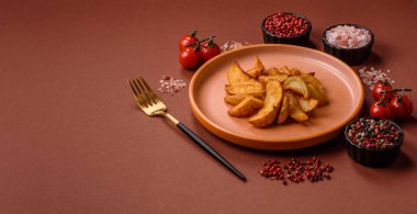 Biberiye, peynir, tuz ve baharatlı ızgara patates dilimleri. Koyu beton zeminde fırında patates dilimleri.