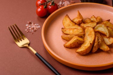 Biberiye, peynir, tuz ve baharatlı ızgara patates dilimleri. Koyu beton zeminde fırında patates dilimleri.