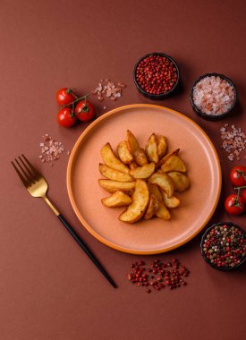 Biberiye, peynir, tuz ve baharatlı ızgara patates dilimleri. Koyu beton zeminde fırında patates dilimleri.