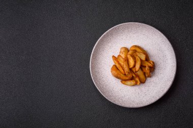 Biberiye, peynir, tuz ve baharatlı ızgara patates dilimleri. Koyu beton zeminde fırında patates dilimleri.