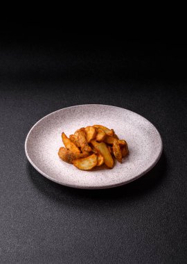 Biberiye, peynir, tuz ve baharatlı ızgara patates dilimleri. Koyu beton zeminde fırında patates dilimleri.