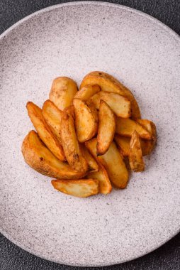 Biberiye, peynir, tuz ve baharatlı ızgara patates dilimleri. Koyu beton zeminde fırında patates dilimleri.