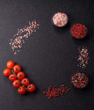 Koyu beton zeminde domates, tuz, baharat ve otlar pişirmek için gerekli malzemeler.