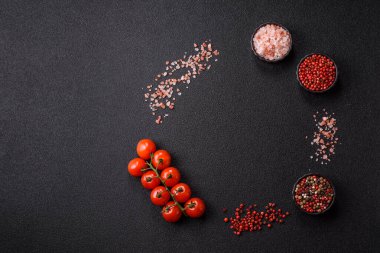 Koyu beton zeminde domates, tuz, baharat ve otlar pişirmek için gerekli malzemeler.