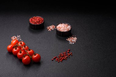 Koyu beton zeminde domates, tuz, baharat ve otlar pişirmek için gerekli malzemeler.