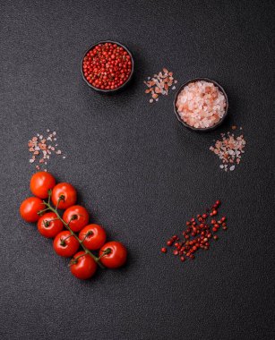 Koyu beton zeminde domates, tuz, baharat ve otlar pişirmek için gerekli malzemeler.