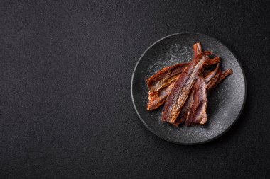 Atıştırmalık olarak kurutulmuş balık veya kurutulmuş et, dilimlenmiş deniz ürünleri. Tasarımınız için arka plan olarak kurutulmuş deniz ürünleri atıştırmalıkları