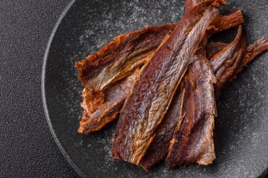 Atıştırmalık olarak kurutulmuş balık veya kurutulmuş et, dilimlenmiş deniz ürünleri. Tasarımınız için arka plan olarak kurutulmuş deniz ürünleri atıştırmalıkları