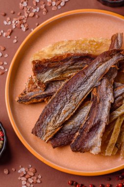 Atıştırmalık olarak kurutulmuş balık veya kurutulmuş et, dilimlenmiş deniz ürünleri. Tasarımınız için arka plan olarak kurutulmuş deniz ürünleri atıştırmalıkları