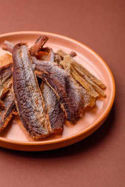 Atıştırmalık olarak kurutulmuş balık veya kurutulmuş et, dilimlenmiş deniz ürünleri. Tasarımınız için arka plan olarak kurutulmuş deniz ürünleri atıştırmalıkları