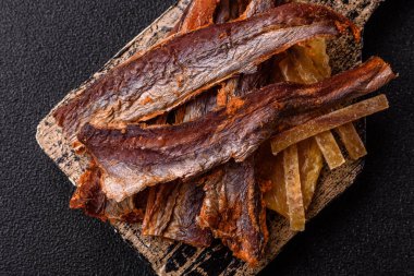 Atıştırmalık olarak kurutulmuş balık veya kurutulmuş et, dilimlenmiş deniz ürünleri. Tasarımınız için arka plan olarak kurutulmuş deniz ürünleri atıştırmalıkları