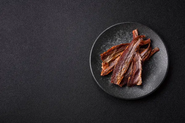 Atıştırmalık olarak kurutulmuş balık veya kurutulmuş et, dilimlenmiş deniz ürünleri. Tasarımınız için arka plan olarak kurutulmuş deniz ürünleri atıştırmalıkları