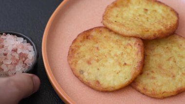 Mücver, patates, soğan ve sebzeden yapılmış kahvaltı yemeği. Koyu beton arka planda patates, tuz ve baharatlı mücver.