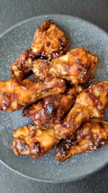Izgara ya da ızgara tavuk kanadı, teriyaki sosu, baharat ve susam tohumuyla. Koyu arkaplanda tuz ve baharatlı Teriyaki tavuğu
