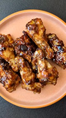 Izgara ya da ızgara tavuk kanadı, teriyaki sosu, baharat ve susam tohumuyla. Koyu arkaplanda tuz ve baharatlı Teriyaki tavuğu
