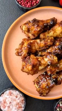 Izgara ya da ızgara tavuk kanadı, teriyaki sosu, baharat ve susam tohumuyla. Koyu arkaplanda tuz ve baharatlı Teriyaki tavuğu