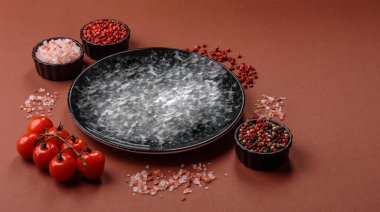 Yemek için boş yuvarlak siyah tabak, yemek masasında mutfak gereçleri. Koyu arkaplanda boş tabak