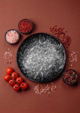 Yemek için boş yuvarlak siyah tabak, yemek masasında mutfak gereçleri. Koyu arkaplanda boş tabak