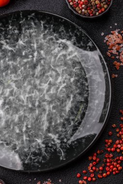 Yemek için boş yuvarlak siyah tabak, yemek masasında mutfak gereçleri. Koyu arkaplanda boş tabak