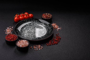 Yemek için boş yuvarlak siyah tabak, yemek masasında mutfak gereçleri. Koyu arkaplanda boş tabak