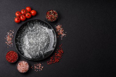 Yemek için boş yuvarlak siyah tabak, yemek masasında mutfak gereçleri. Koyu arkaplanda boş tabak