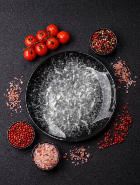 Yemek için boş yuvarlak siyah tabak, yemek masasında mutfak gereçleri. Koyu arkaplanda boş tabak