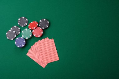 Kumarhanede poker oynuyorum. Fişler, bahisler ve risklerle. Yeşil kartlar ve çipler tasarımınız için arka plan görevi görür