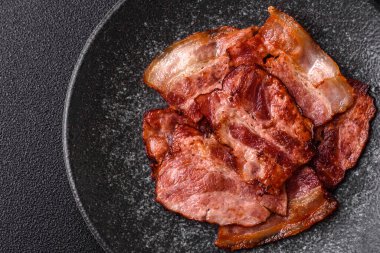 Lezzetli bir İngiliz kahvaltısının malzemesi olarak kızarmış domuz pastırması. Tasarımın için arka plan olarak kızarmış pastırma parçaları.