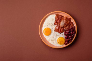 Yağda yumurta, pastırma ve fasulye, domates ve soslu klasik bir İngiliz kahvaltısı. Yumurta, pastırma ve fasulye güne başlamak için sağlıklı bir yemek.