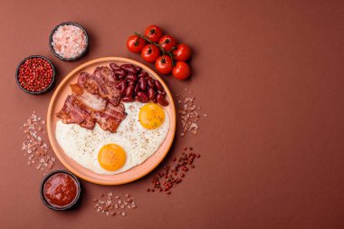 Yağda yumurta, pastırma ve fasulye, domates ve soslu klasik bir İngiliz kahvaltısı. Yumurta, pastırma ve fasulye güne başlamak için sağlıklı bir yemek.