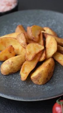 Biberiye, peynir, tuz ve baharatlı ızgara patates dilimleri. Koyu beton zeminde fırında patates dilimleri.