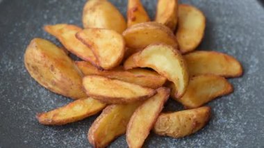 Biberiye, peynir, tuz ve baharatlı ızgara patates dilimleri. Koyu beton zeminde fırında patates dilimleri.