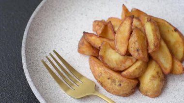 Biberiye, peynir, tuz ve baharatlı ızgara patates dilimleri. Koyu beton zeminde fırında patates dilimleri.