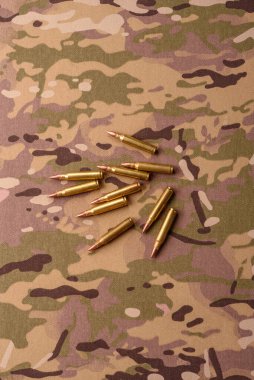 Kamuflaj arka planında makineli tüfek fişekleri, askeri duvar kağıtları. Tasarımınız için bir kamuflaj arkaplanı