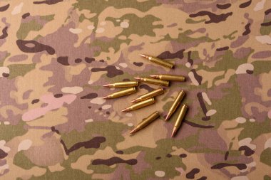 Kamuflaj arka planında makineli tüfek fişekleri, askeri duvar kağıtları. Tasarımınız için bir kamuflaj arkaplanı