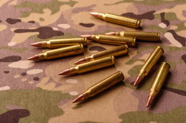 Kamuflaj arka planında makineli tüfek fişekleri, askeri duvar kağıtları. Tasarımınız için bir kamuflaj arkaplanı