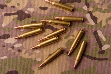 Kamuflaj arka planında makineli tüfek fişekleri, askeri duvar kağıtları. Tasarımınız için bir kamuflaj arkaplanı