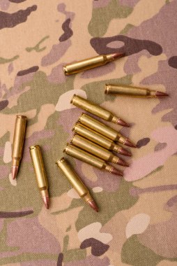 Kamuflaj arka planında makineli tüfek fişekleri, askeri duvar kağıtları. Tasarımınız için bir kamuflaj arkaplanı