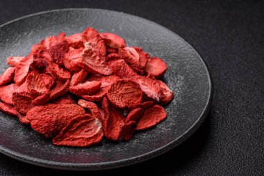 Tatlı tatlılar için bir malzeme olarak kurumuş sublimleşmiş çilek dilimleri. Tasarımınız için yemek arkaplanı olarak kurutulmuş çilek