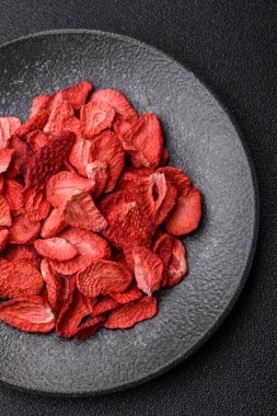 Tatlı tatlılar için bir malzeme olarak kurumuş sublimleşmiş çilek dilimleri. Tasarımınız için yemek arkaplanı olarak kurutulmuş çilek