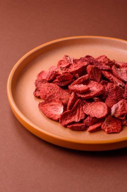 Tatlı tatlılar için bir malzeme olarak kurumuş sublimleşmiş çilek dilimleri. Tasarımınız için yemek arkaplanı olarak kurutulmuş çilek