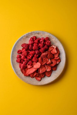 Tatlı tatlılar için bir malzeme olarak kurumuş sublimleşmiş çilek dilimleri. Kurutulmuş çilek ve ahududu, tasarımınız için gıda arka planıdır.