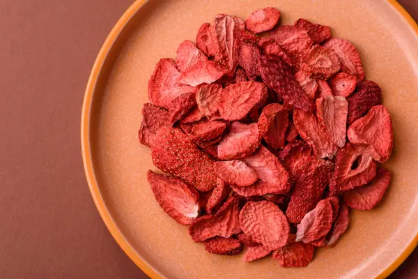 Tatlı tatlılar için bir malzeme olarak kurumuş sublimleşmiş çilek dilimleri. Tasarımınız için yemek arkaplanı olarak kurutulmuş çilek