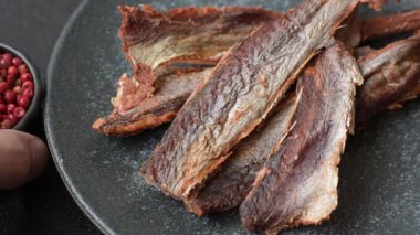 Atıştırmalık olarak kurutulmuş balık veya kurutulmuş et, dilimlenmiş deniz ürünleri. Tasarımınız için arka plan olarak kurutulmuş deniz ürünleri atıştırmalıkları