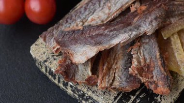 Atıştırmalık olarak kurutulmuş balık veya kurutulmuş et, dilimlenmiş deniz ürünleri. Tasarımınız için arka plan olarak kurutulmuş deniz ürünleri atıştırmalıkları