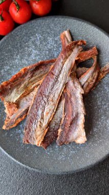 Atıştırmalık olarak kurutulmuş balık veya kurutulmuş et, dilimlenmiş deniz ürünleri. Tasarımınız için arka plan olarak kurutulmuş deniz ürünleri atıştırmalıkları