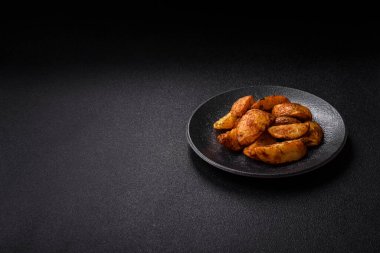 Baharatlı, sarımsaklı ve biberiyeli patates dilimleri. Tasarımınız için yemek arkaplanı olarak patates dilimleri
