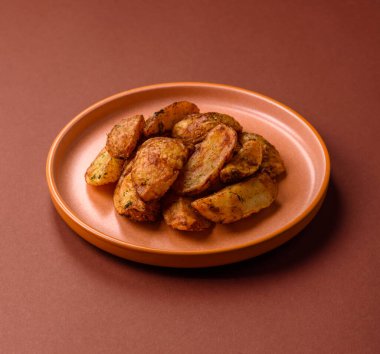 Baharatlı, sarımsaklı ve biberiyeli patates dilimleri. Tasarımınız için yemek arkaplanı olarak patates dilimleri