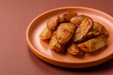 Baharatlı, sarımsaklı ve biberiyeli patates dilimleri. Tasarımınız için yemek arkaplanı olarak patates dilimleri